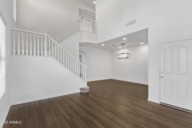 unfurnished living room featuring a towering ceiling and dark hardwood / wood-style flooring