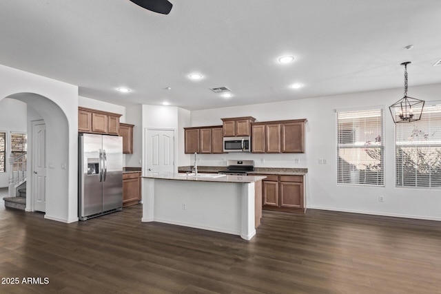 kitchen featuring dark wood-type flooring, sink, appliances with stainless steel finishes, an island with sink, and pendant lighting