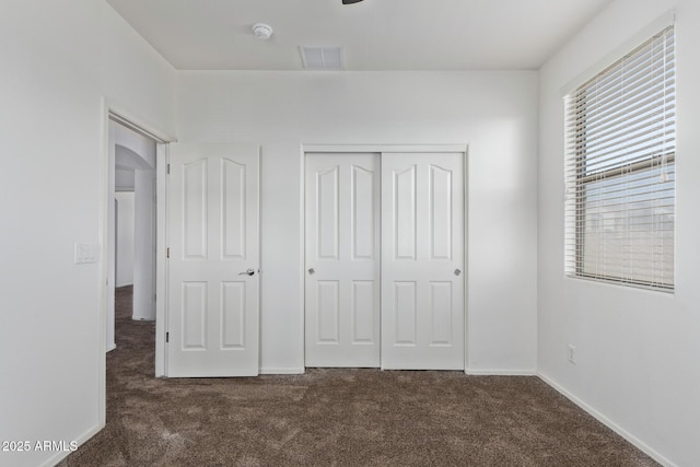 unfurnished bedroom with dark carpet and a closet