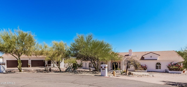view of front of property with stucco siding, a tile roof, a chimney, and driveway