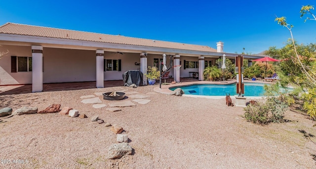 pool featuring an outdoor fire pit, ceiling fan, and a patio