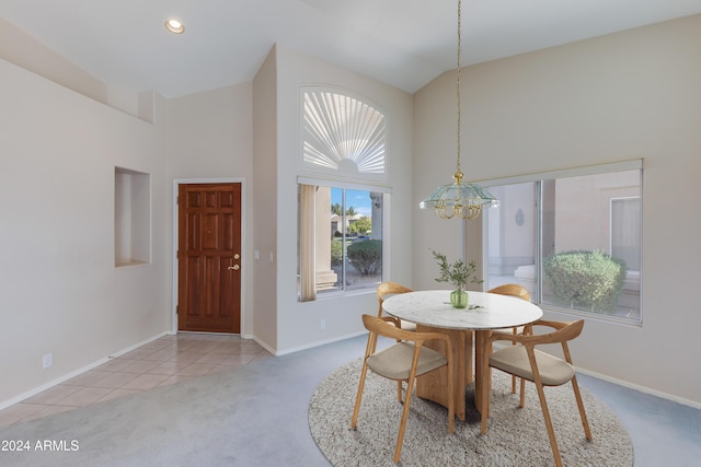 dining space with high vaulted ceiling, light colored carpet, and a notable chandelier