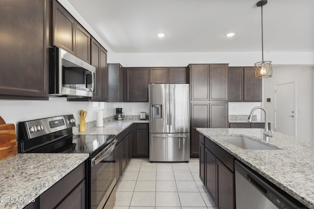 17721 W Cassia Way, Goodyear, AZ 85338 - kitchen with stainless steel appliances, light tile patterned floors, dark brown cabinetry, hanging light fixtures, and light stone counters