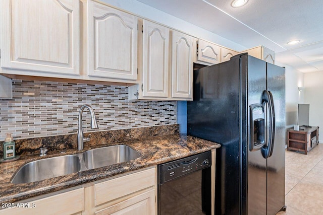 kitchen featuring tasteful backsplash, dark stone countertops, light tile patterned flooring, black appliances, and a sink