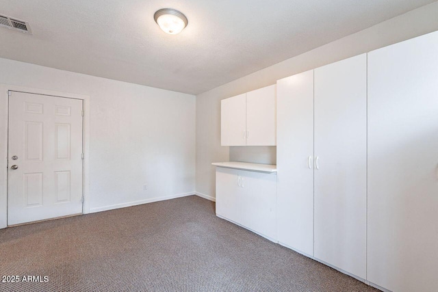 carpeted empty room with baseboards, visible vents, and a textured ceiling