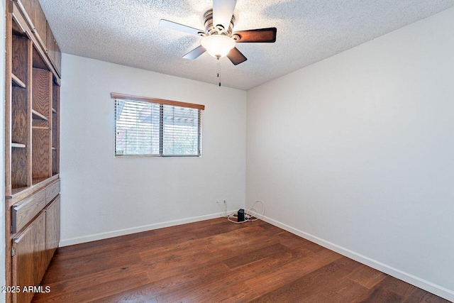 unfurnished room with a textured ceiling, dark wood-type flooring, baseboards, and ceiling fan