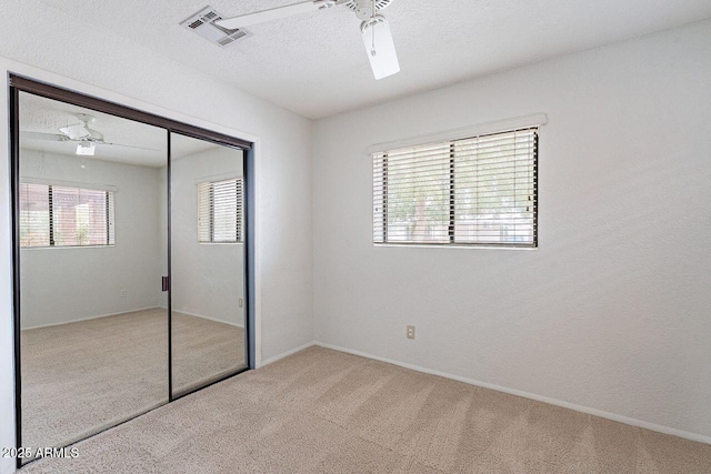 unfurnished bedroom with visible vents, carpet floors, a closet, a textured ceiling, and a ceiling fan