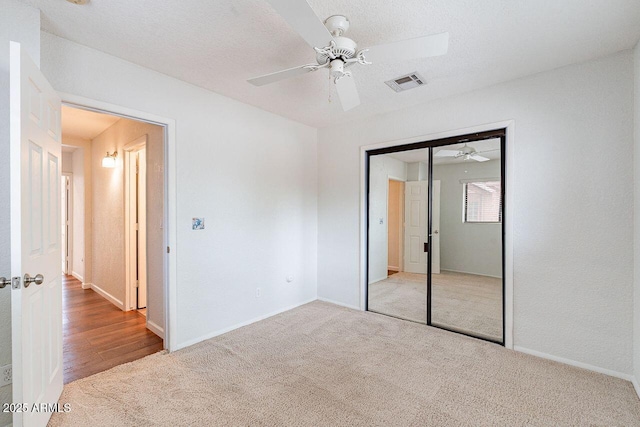 unfurnished bedroom featuring visible vents, a closet, carpet, baseboards, and ceiling fan