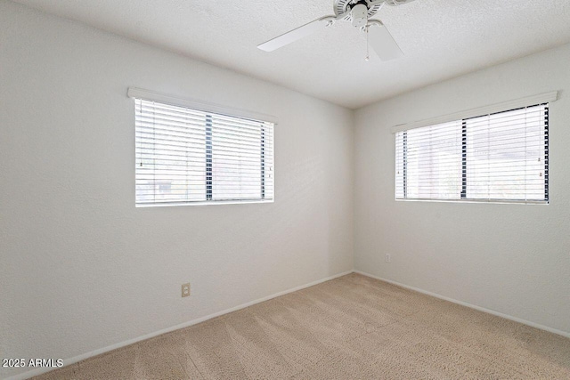 spare room featuring baseboards, light carpet, a textured ceiling, and ceiling fan