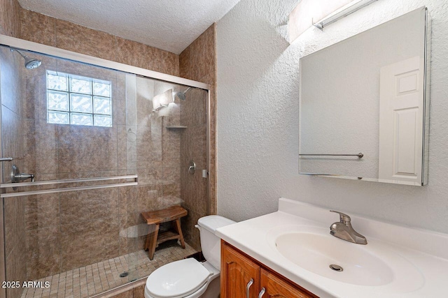 full bath featuring a shower stall, toilet, vanity, a textured wall, and a textured ceiling