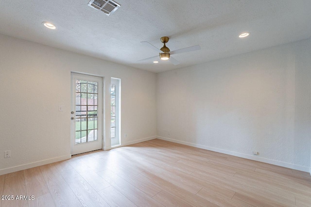 unfurnished room with baseboards, visible vents, ceiling fan, a textured ceiling, and light wood-type flooring