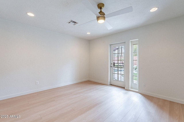 empty room with a ceiling fan, a textured ceiling, recessed lighting, light wood finished floors, and baseboards