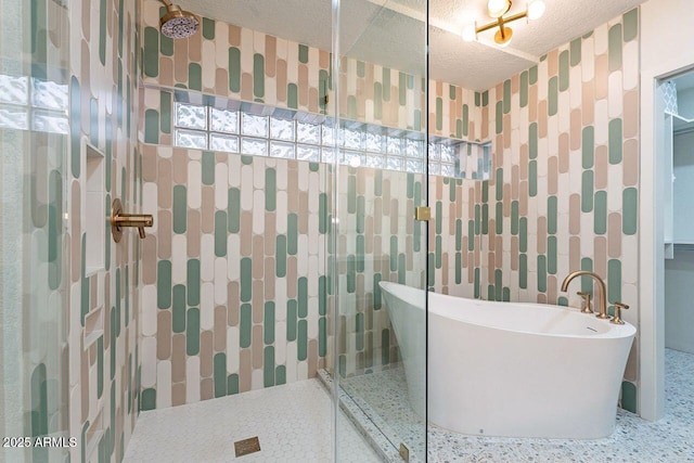 bathroom with a textured ceiling, tile walls, a tile shower, and a freestanding bath