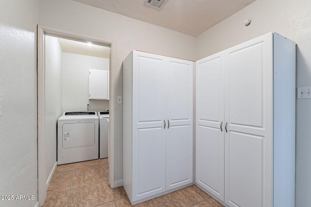 washroom featuring visible vents, a textured ceiling, cabinet space, separate washer and dryer, and baseboards