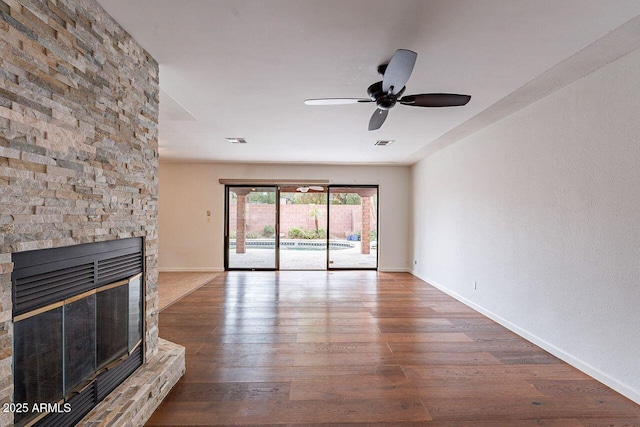 unfurnished living room with visible vents, a ceiling fan, wood finished floors, a fireplace, and baseboards