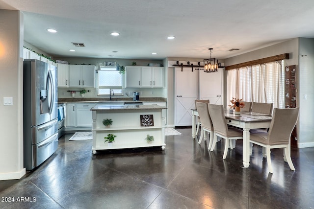 dining space with a barn door, sink, and a notable chandelier