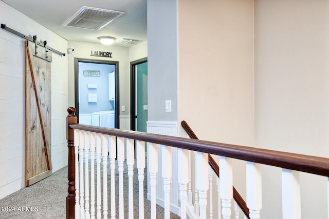 hall with a barn door and carpet