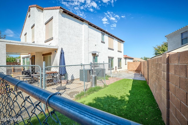 rear view of property featuring a patio and a yard