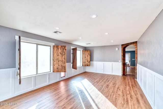 775 E Leslie Ave, San Tan Valley, AZ 85140 - unfurnished room featuring arched walkways, a decorative wall, light wood finished floors, wainscoting, and recessed lighting