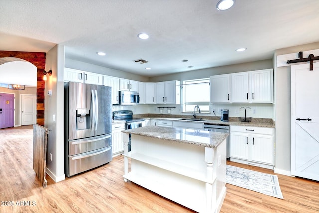 775 E Leslie Ave, San Tan Valley, AZ 85140 - kitchen with appliances with stainless steel finishes, a sink, open shelves, light wood-style flooring, and light stone counters