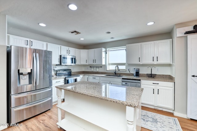 775 E Leslie Ave, San Tan Valley, AZ 85140 - kitchen with appliances with stainless steel finishes, a sink, light stone counters, white cabinetry, and light wood-style floors