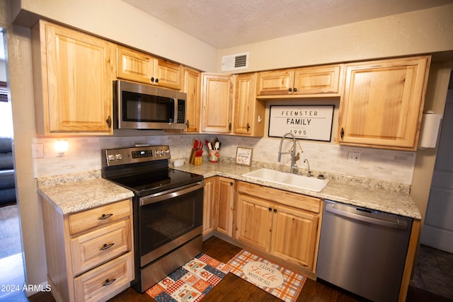 kitchen featuring tasteful backsplash, light brown cabinets, appliances with stainless steel finishes, and sink