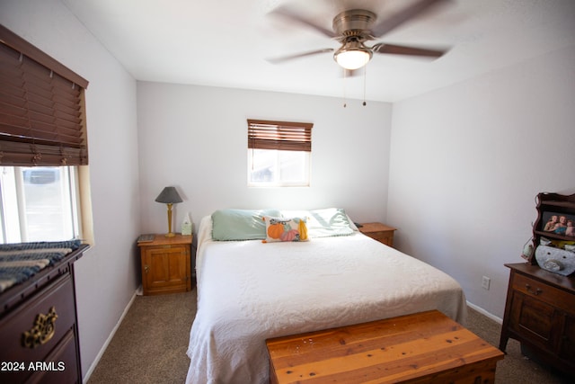 bedroom with multiple windows, ceiling fan, and dark carpet