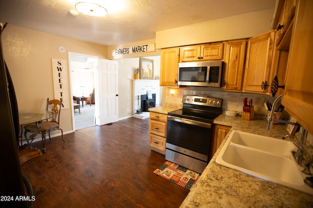 kitchen with sink, appliances with stainless steel finishes, a textured ceiling, dark wood-type flooring, and decorative backsplash