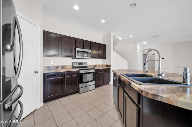 kitchen featuring light countertops, appliances with stainless steel finishes, a sink, and dark brown cabinetry