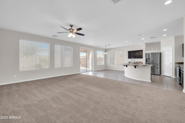 unfurnished living room with light carpet, recessed lighting, a sink, and light tile patterned flooring