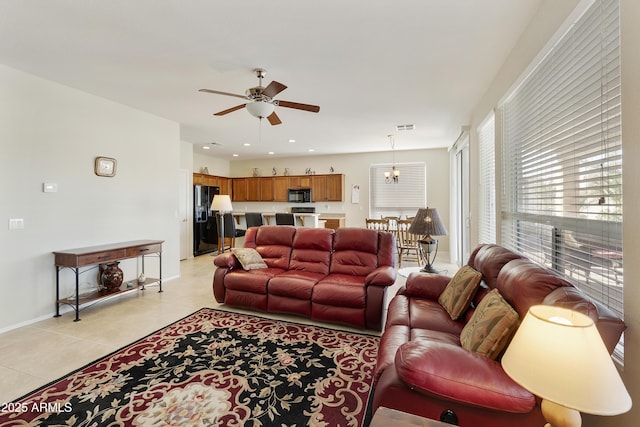 living room with light tile patterned floors, recessed lighting, ceiling fan with notable chandelier, visible vents, and baseboards