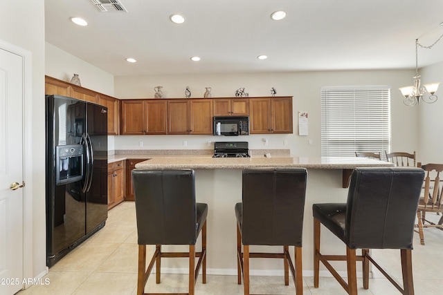 kitchen featuring recessed lighting, a breakfast bar, light countertops, brown cabinets, and black appliances