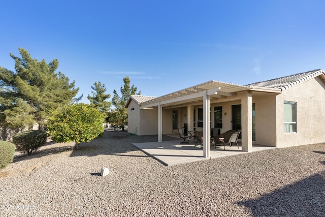 rear view of house with a tiled roof, a pergola, a patio area, and stucco siding