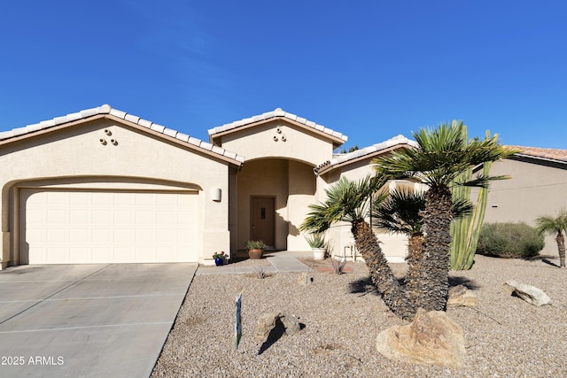 mediterranean / spanish home featuring driveway, an attached garage, a tile roof, and stucco siding