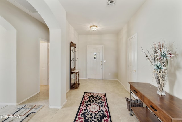 foyer with arched walkways, light tile patterned floors, visible vents, and baseboards