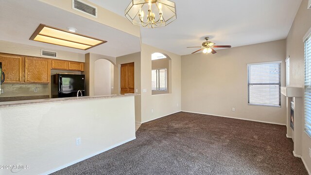 1909 N 106th Ave, Avondale, AZ 85392 - kitchen featuring visible vents, dark colored carpet, freestanding refrigerator, brown cabinetry, and ceiling fan with notable chandelier
