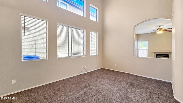 1909 N 106th Ave, Avondale, AZ 85392 - carpeted empty room featuring baseboards, arched walkways, a high ceiling, a tiled fireplace, and a ceiling fan