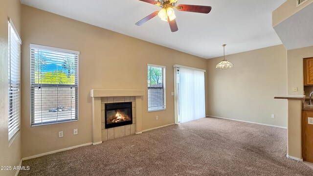 1909 N 106th Ave, Avondale, AZ 85392 - unfurnished living room with a tiled fireplace, ceiling fan, carpet floors, and a healthy amount of sunlight
