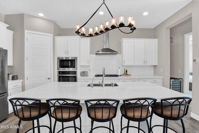 3915 N Shannon Cir, Mesa, AZ 85215 - kitchen featuring stainless steel appliances, beverage cooler, wood finished floors, wall chimney range hood, and decorative backsplash