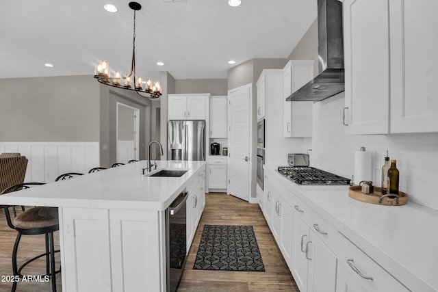 3915 N Shannon Cir, Mesa, AZ 85215 - kitchen with wall chimney exhaust hood, stainless steel appliances, a breakfast bar, light countertops, and a wainscoted wall