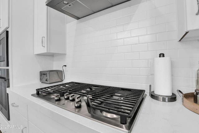 3915 N Shannon Cir, Mesa, AZ 85215 - kitchen view of stainless steel appliances, tasteful backsplash, white cabinetry, and exhaust hood
