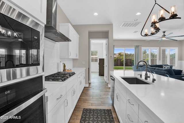 3915 N Shannon Cir, Mesa, AZ 85215 - kitchen featuring wall chimney exhaust hood, stainless steel appliances, light countertops, wood finished floors, and open floor plan