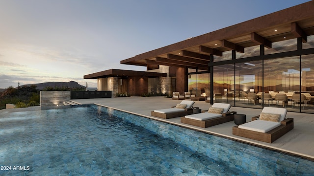 pool at dusk with a mountain view, an outdoor living space, and a patio area