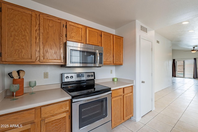 kitchen featuring ceiling fan, stainless steel appliances, and light tile patterned floors