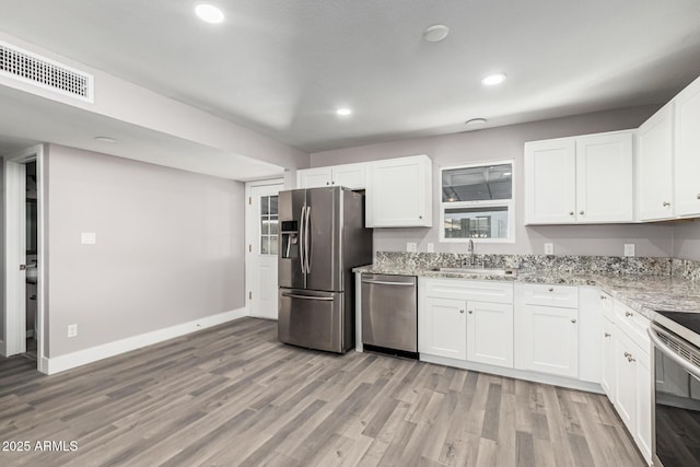 kitchen with light stone counters, stainless steel appliances, sink, and white cabinets