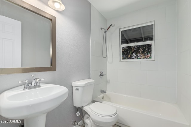 full bathroom with sink, tiled shower / bath combo, and toilet