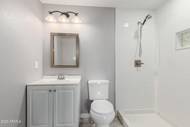 bathroom featuring vanity, tiled shower, and toilet