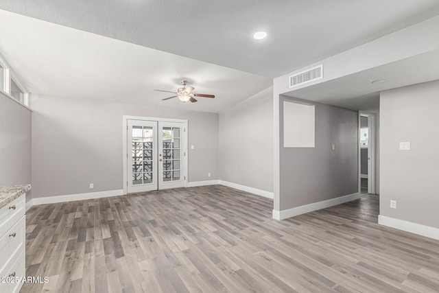 empty room with light hardwood / wood-style floors, french doors, and ceiling fan