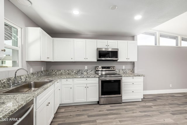 kitchen featuring appliances with stainless steel finishes, a wealth of natural light, sink, and white cabinets