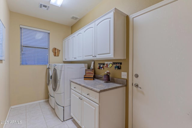 laundry room featuring independent washer and dryer, cabinets, and light tile patterned floors